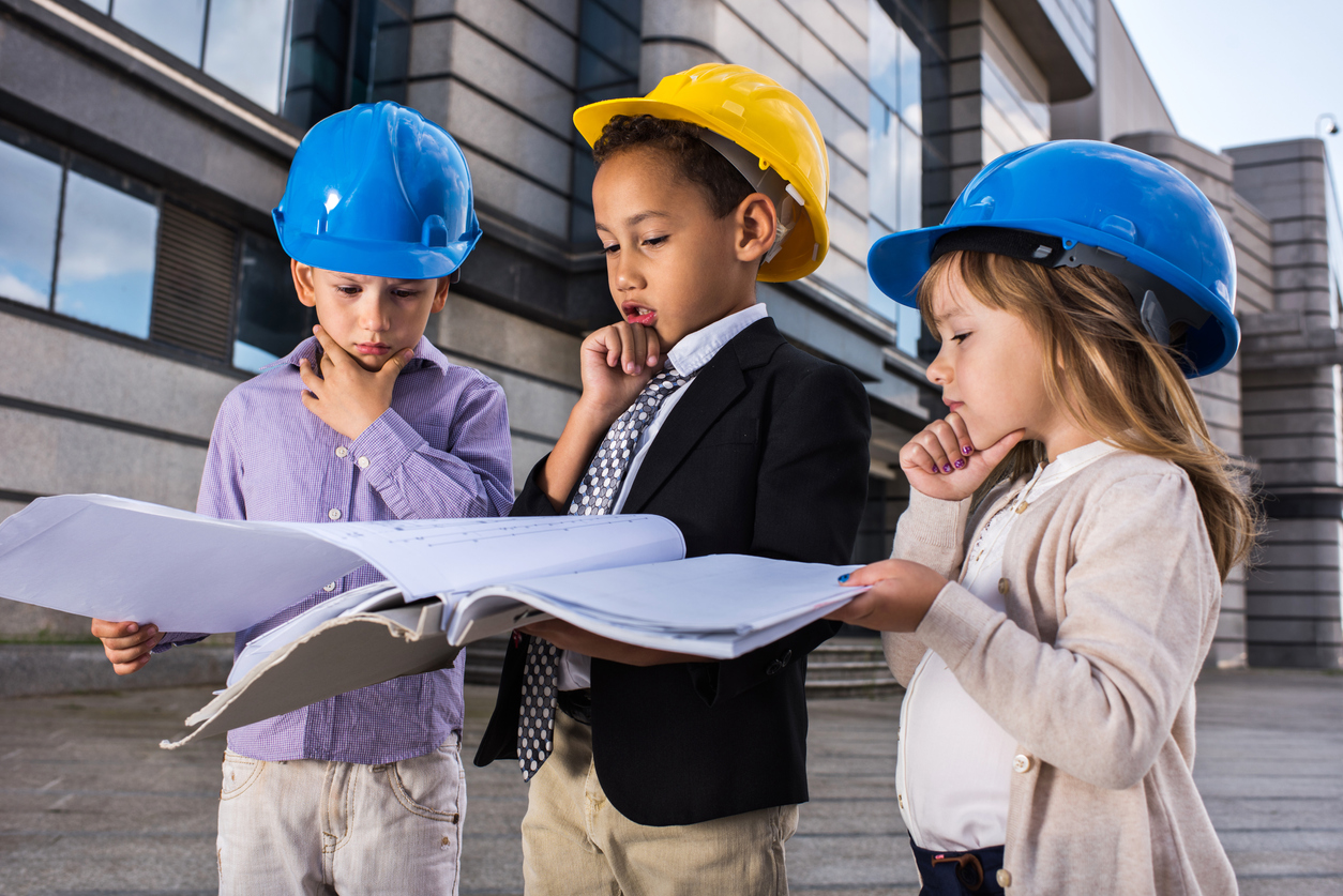 Image of three children in hardhats looking at plans.